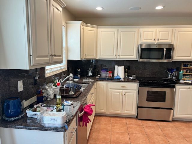 Kitchen with cream cabinets, stainless steel appliances, and dark countertops.