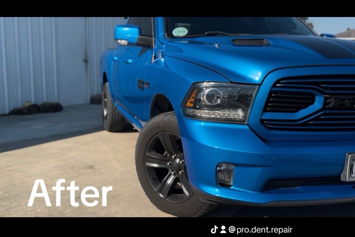 A blue Ram pickup truck parked outdoors, featuring black wheels and a hood stripe, shown after repairs.