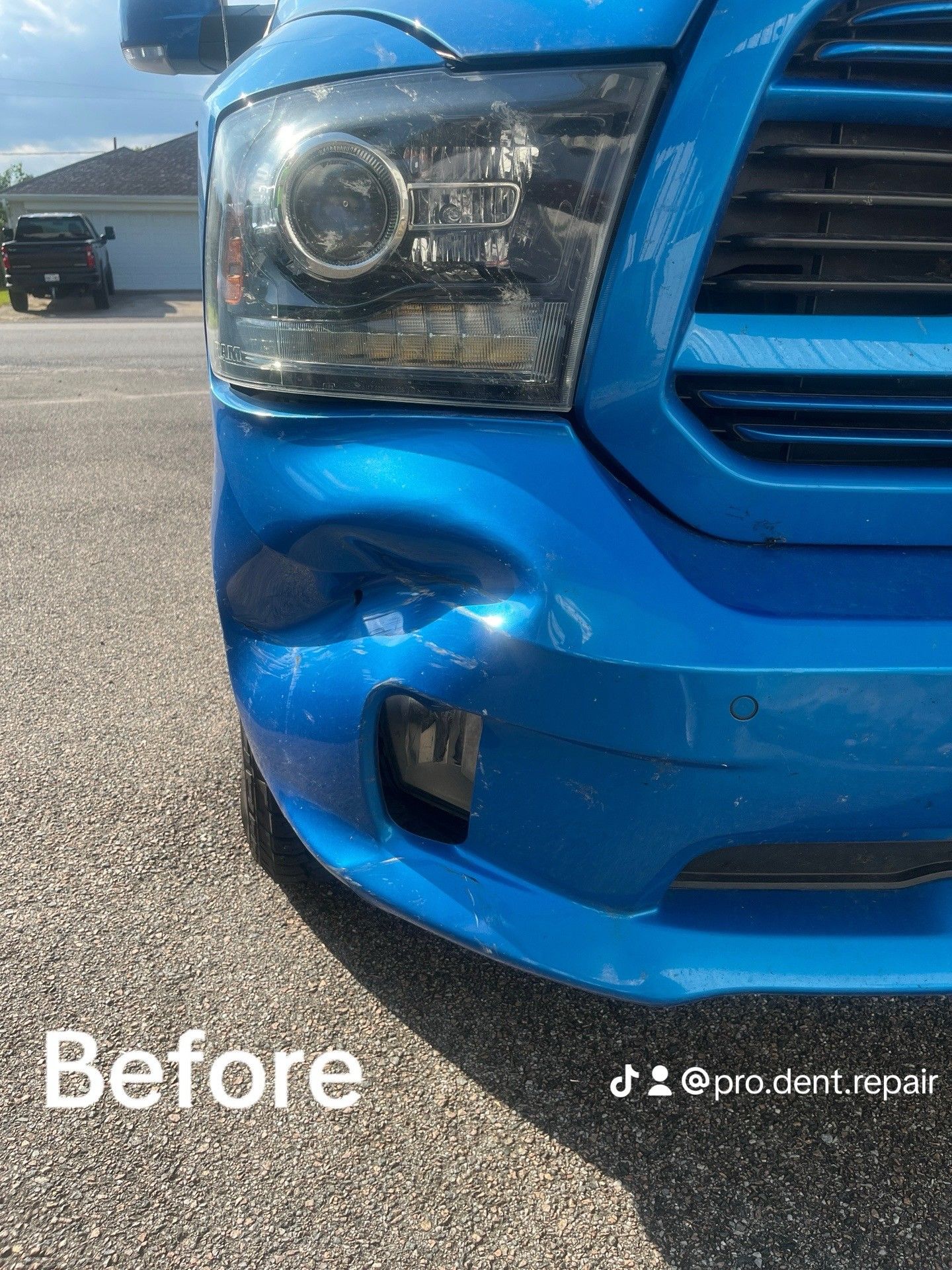Front bumper of a bright blue truck with a visible dent and missing fog light cover, labeled 