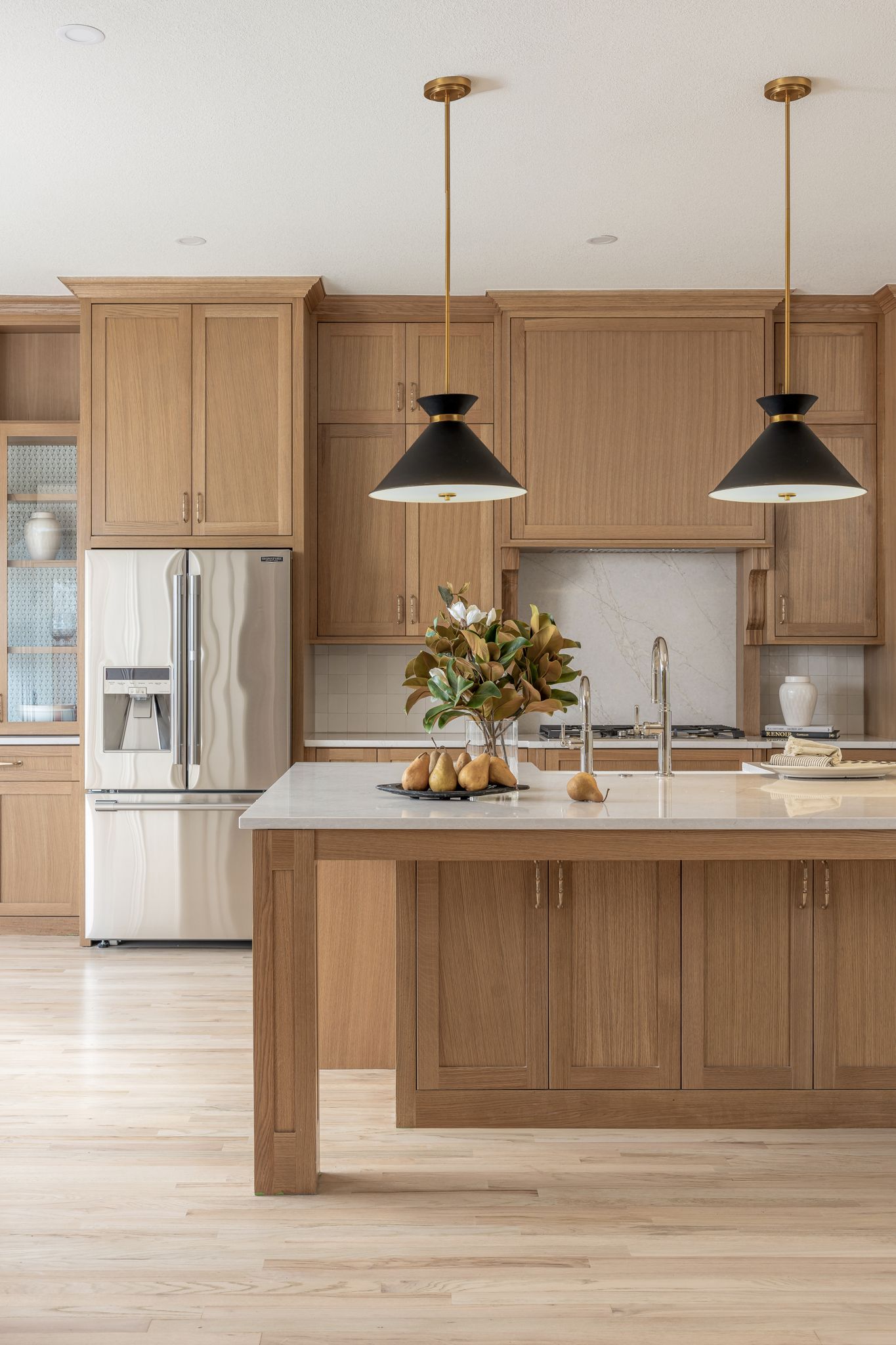 Modern kitchen with wood cabinets, island, and stainless steel refrigerator