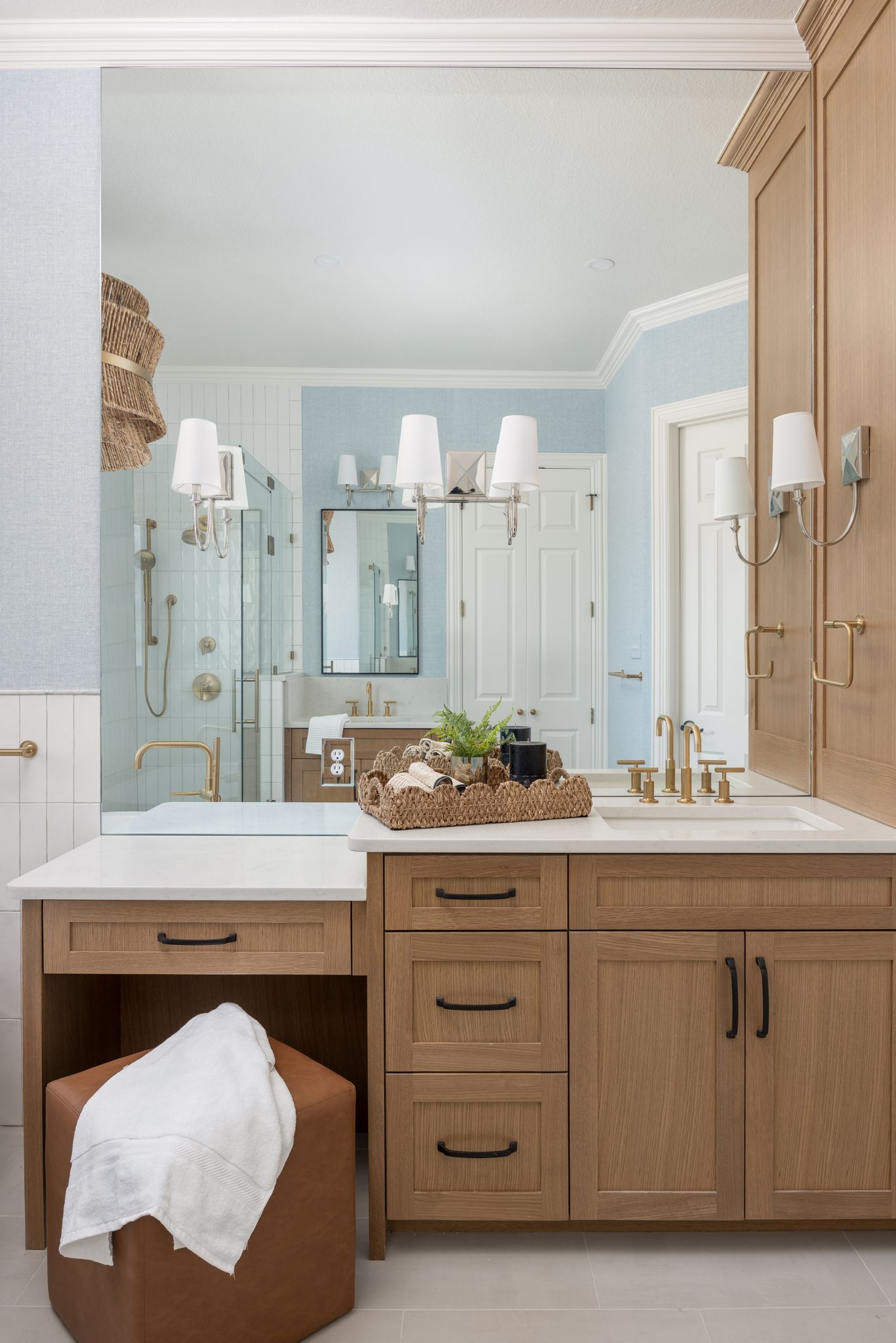 Bathroom with light blue walls, wooden vanity, and large mirror
