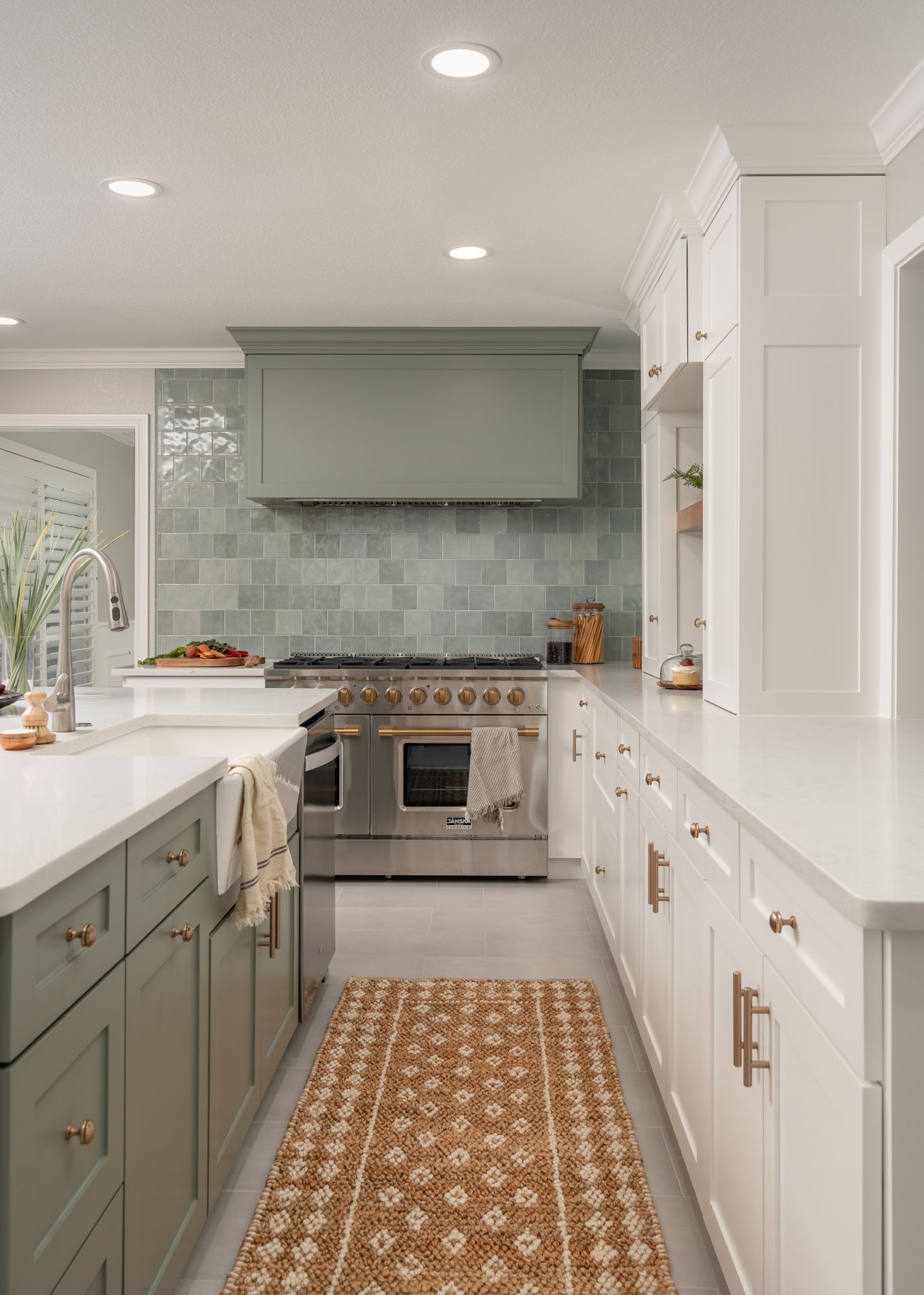 Kitchen with green and white cabinets, stainless steel stove, and patterned runner rug