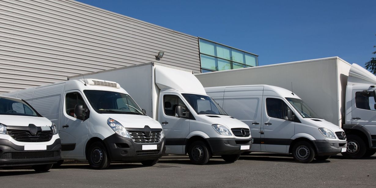 White delivery vans parked in front of a building on a sunny day.