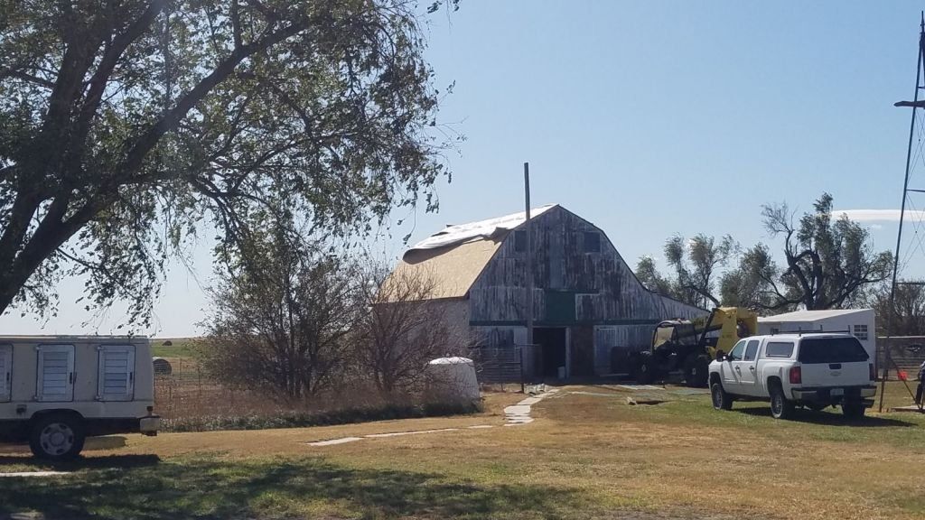 A white truck is parked in front of a barn