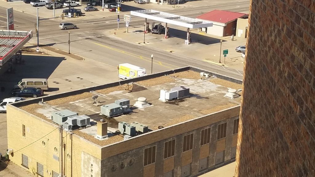 An aerial view of a building with a gas station in the background