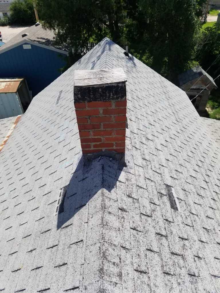 A brick chimney is sitting on top of a roof.