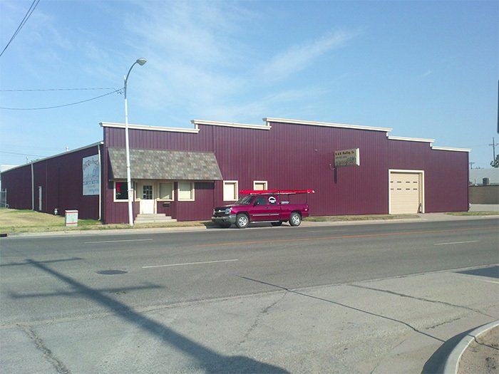 A red truck is parked in front of a purple building.