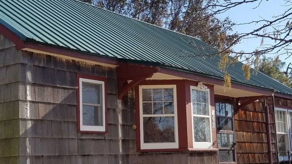A small house with a green roof and red trim