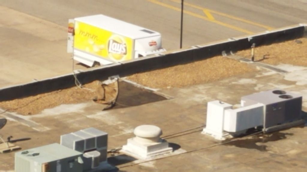 A yellow and white truck is parked on the roof of a building