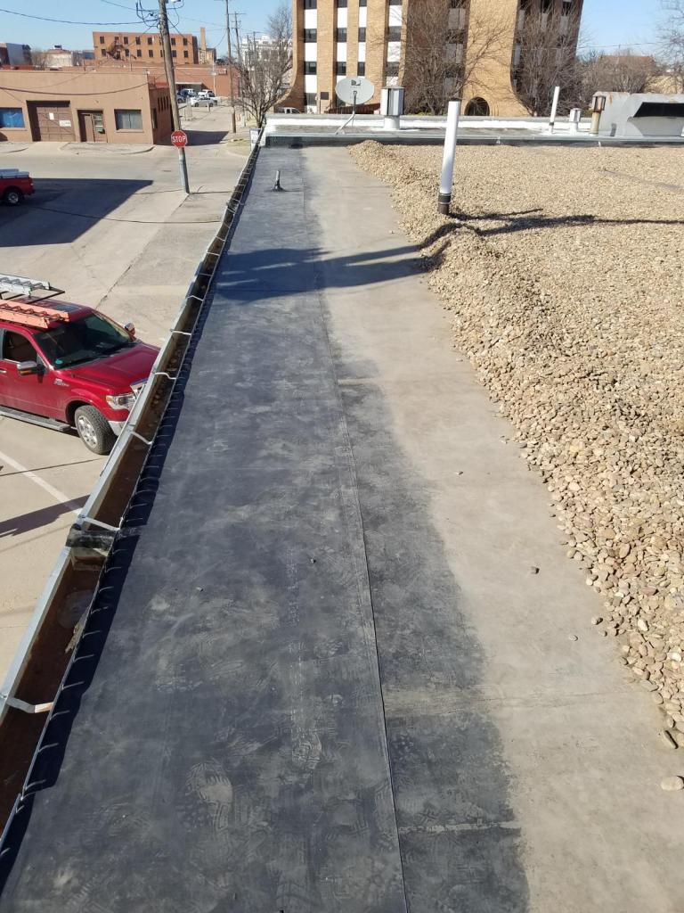A red car is parked on the side of a road next to a building.