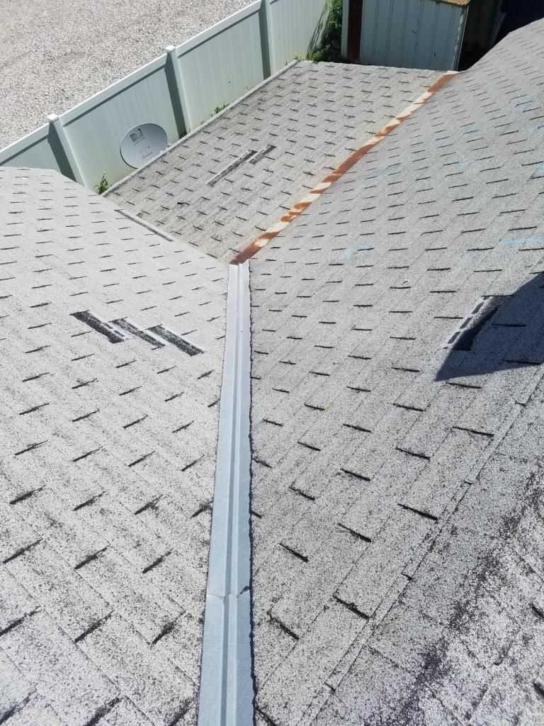A close up of a roof with a white fence in the background.