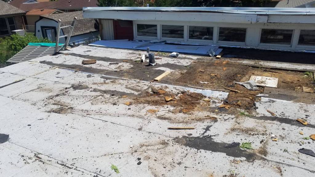 A roof with a lot of dirt on it and a building in the background