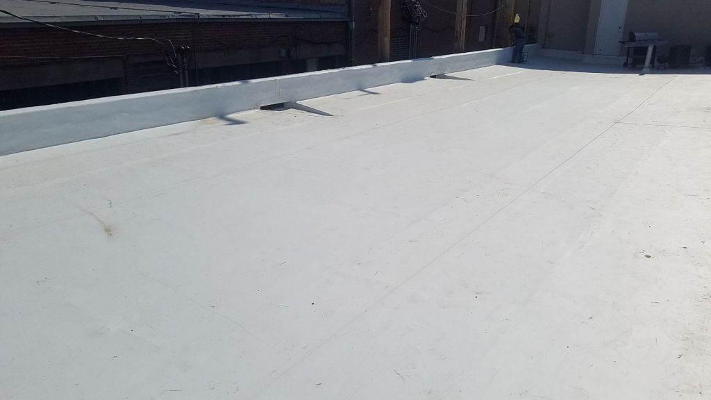 A white roof with a gutter on it is sitting on top of a building.