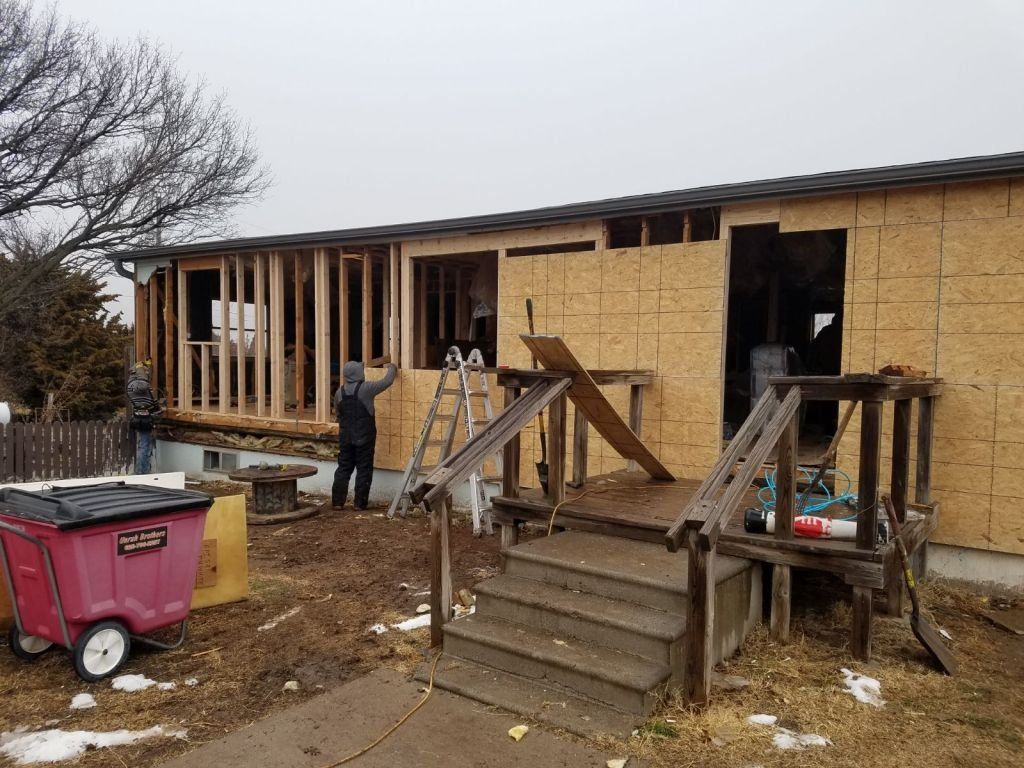 A man is standing in front of a mobile home being remodeled.