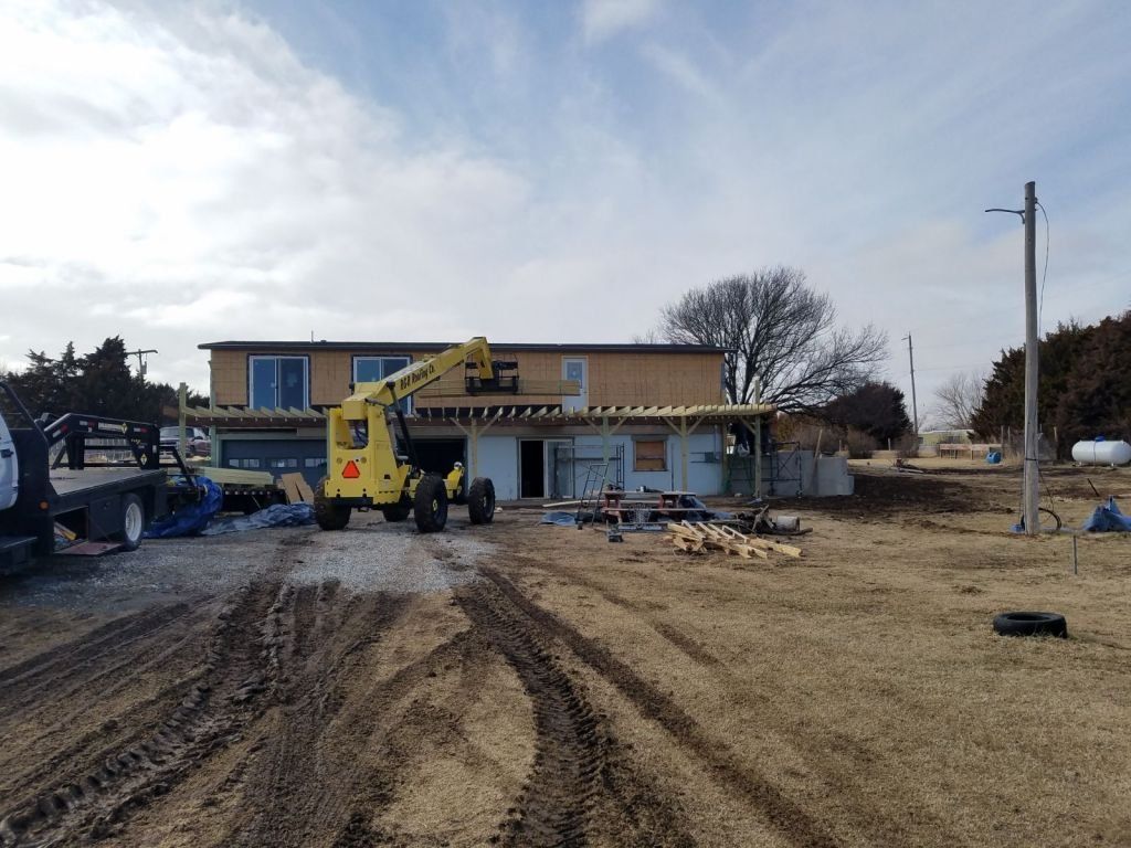 A yellow construction vehicle is parked in front of a building under construction.