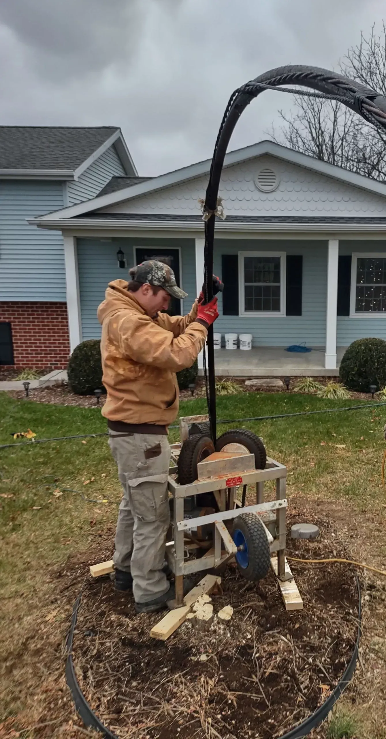 A man is working on a machine in front of a house.