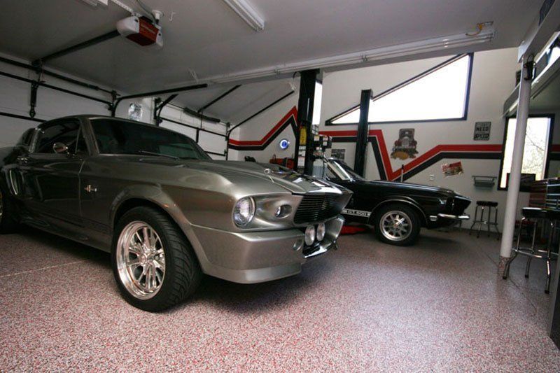 Two mustangs are parked in a garage next to each other