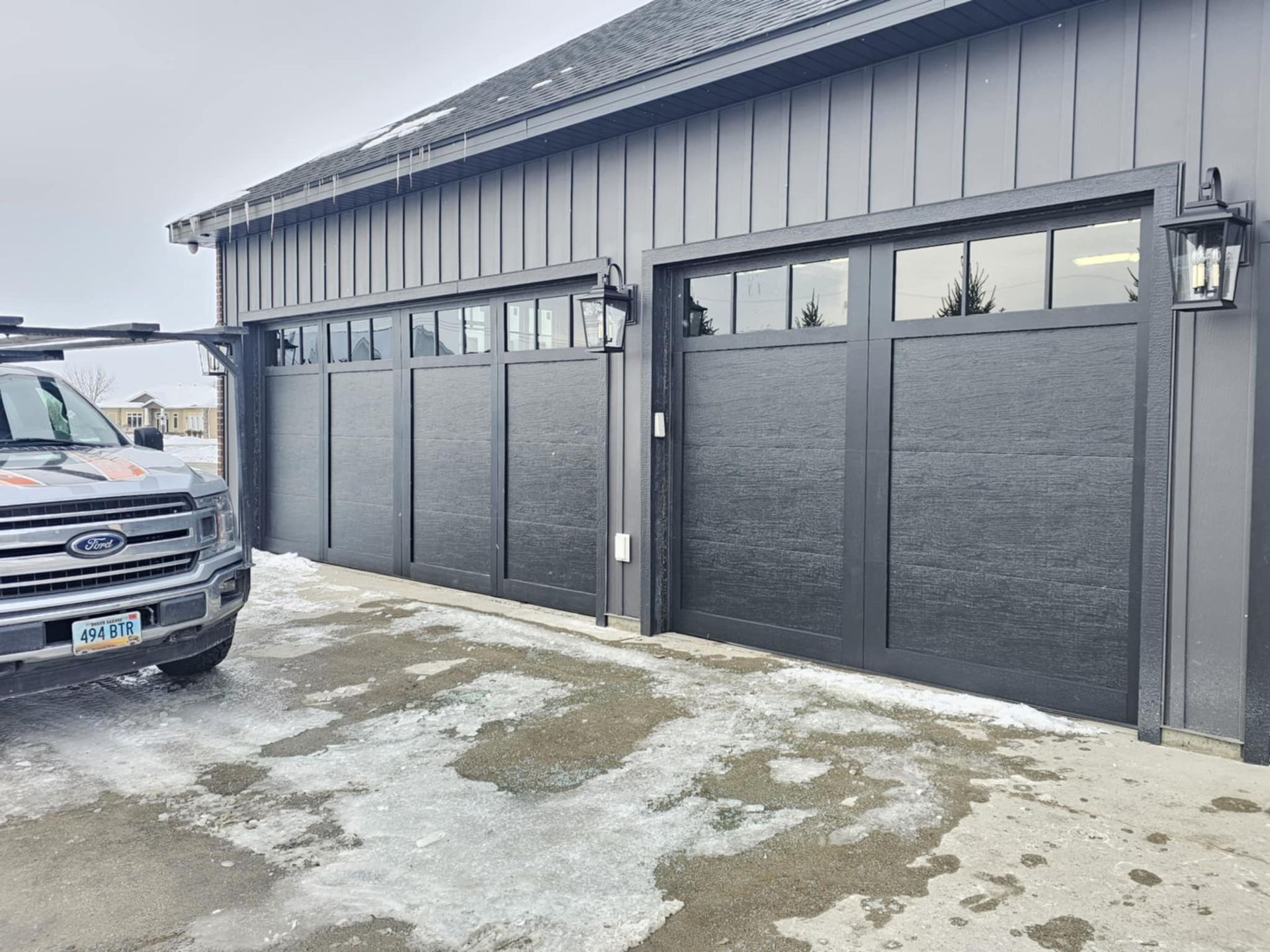 A black truck is parked in front of a black garage door.