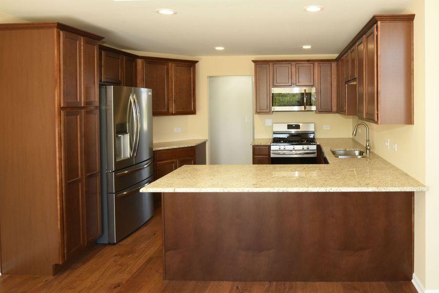 Kitchen with dark wood cabinets, stainless steel appliances, and beige countertop.