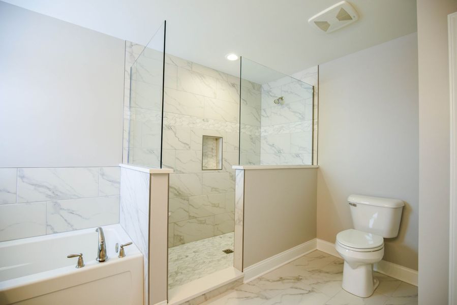 Modern bathroom with marble tile, glass shower, and white toilet.