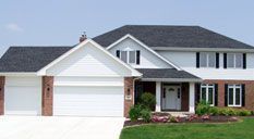 Two-story white house with black roof and garage. Red brick accents, front door and windows.