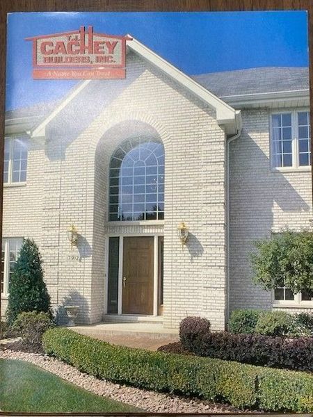 A white brick house with an arched window above the front door. The house has a manicured front yard.