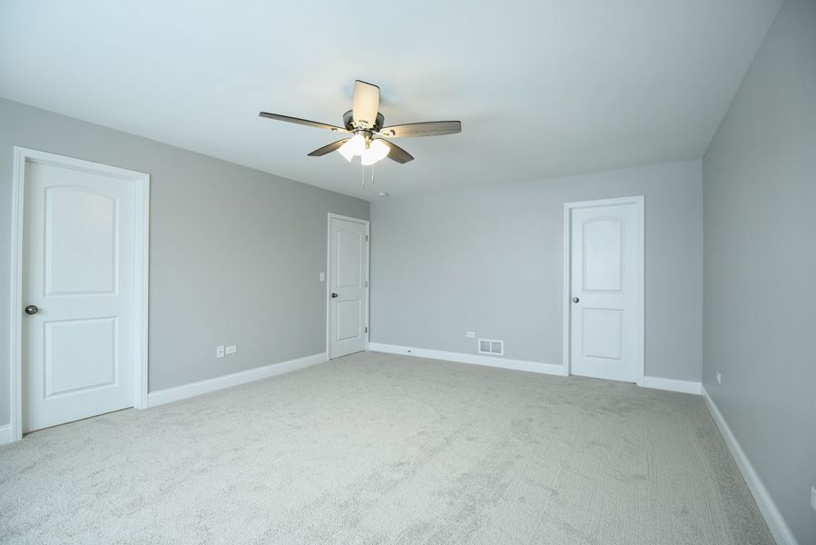 Empty bedroom with gray walls, white doors, and a ceiling fan.