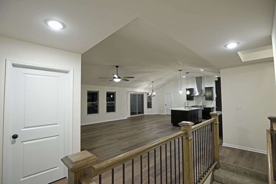 Interior view of a modern home with hardwood floors, a kitchen, and a staircase.