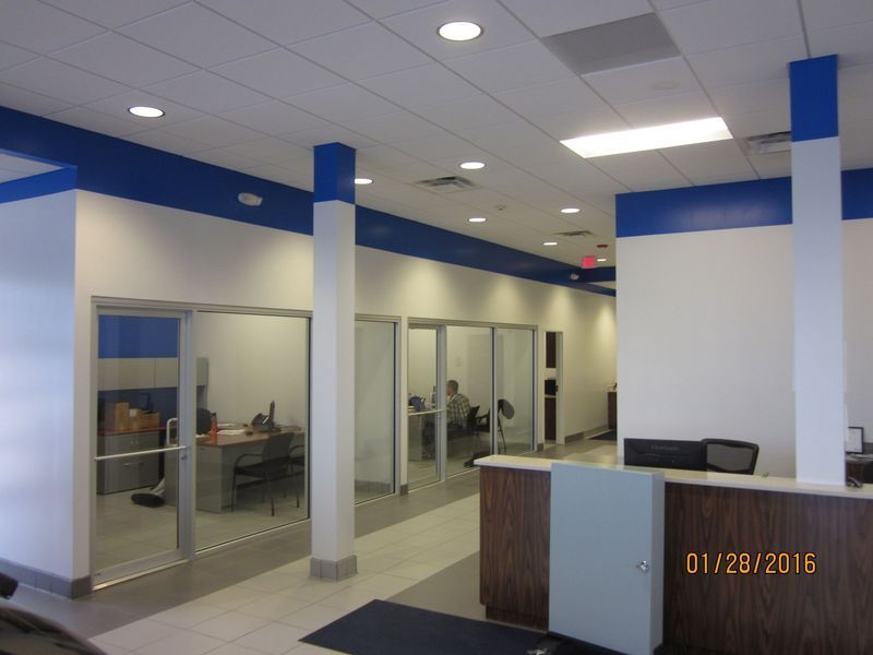 Interior view of a car dealership's office space with blue and white walls and glass-walled offices.