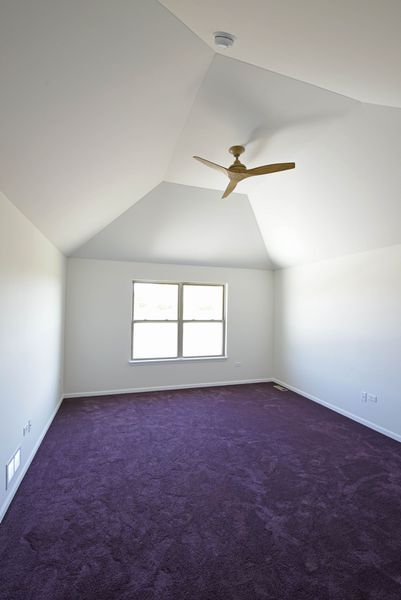 Empty bedroom with purple carpet, white walls, and a ceiling fan.