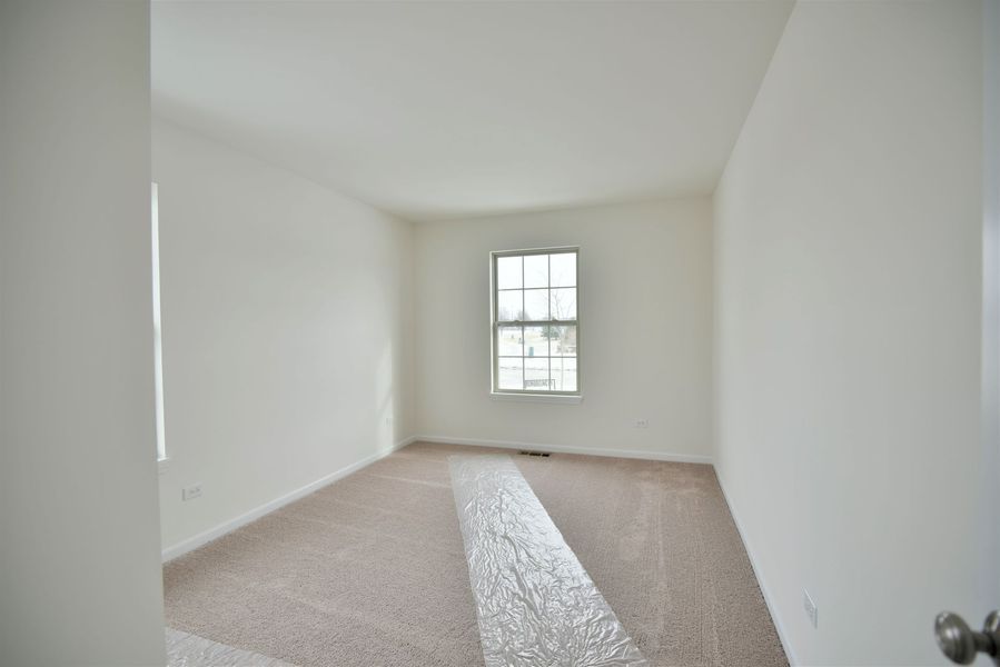 Empty room with beige carpet, white walls, and a window.