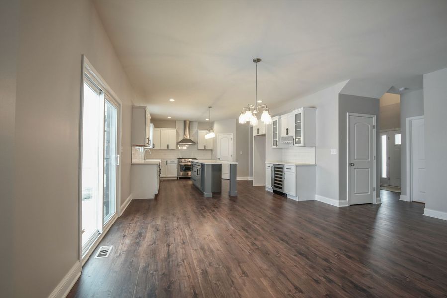Open-concept kitchen and living area with wood flooring, white cabinets, and a gray island.