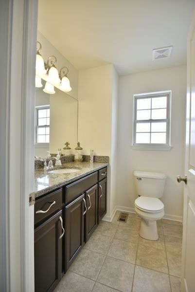 Bathroom with dark brown cabinets, a white toilet, and a window.