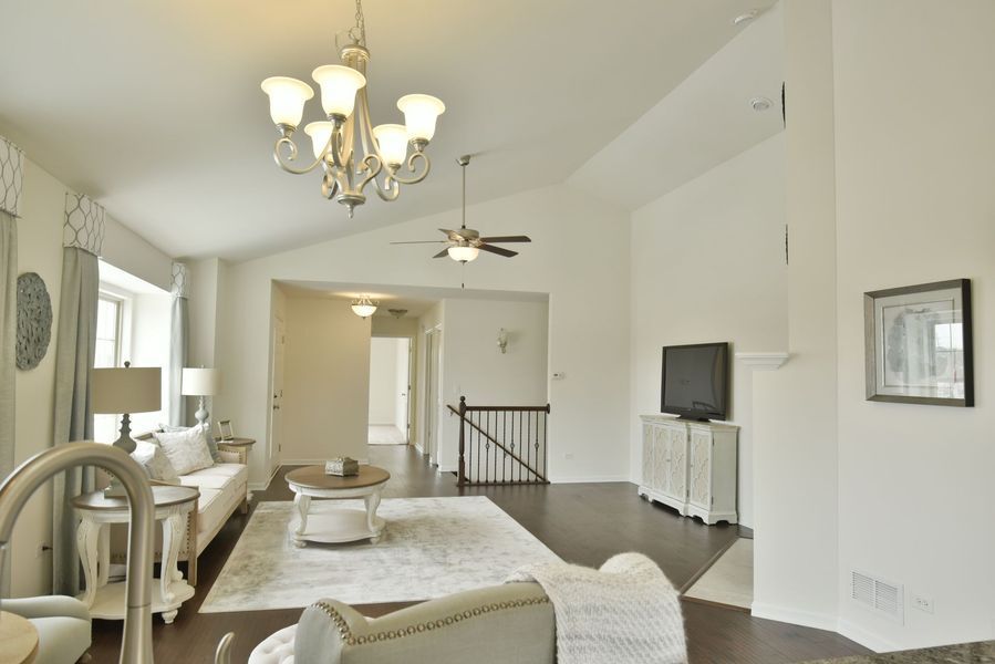 Living room with white walls, chandelier, sofa, TV, and rug.