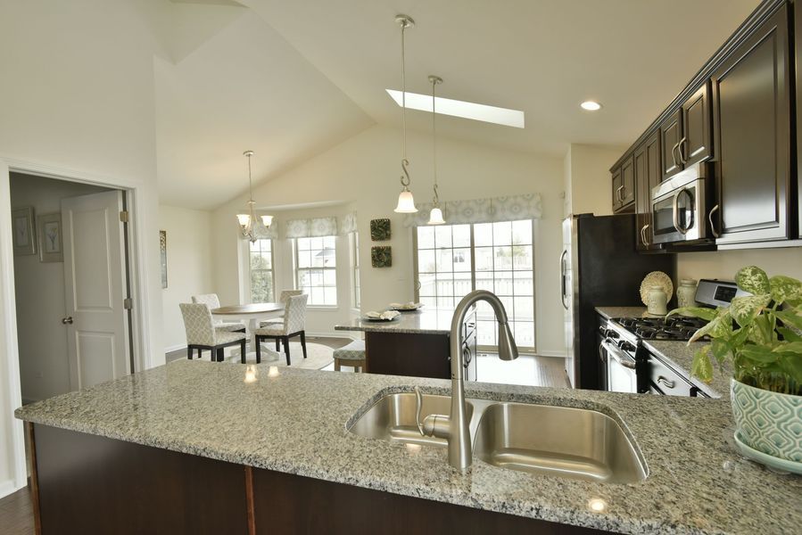 Kitchen with granite countertop, dark cabinets, island, and dining area.