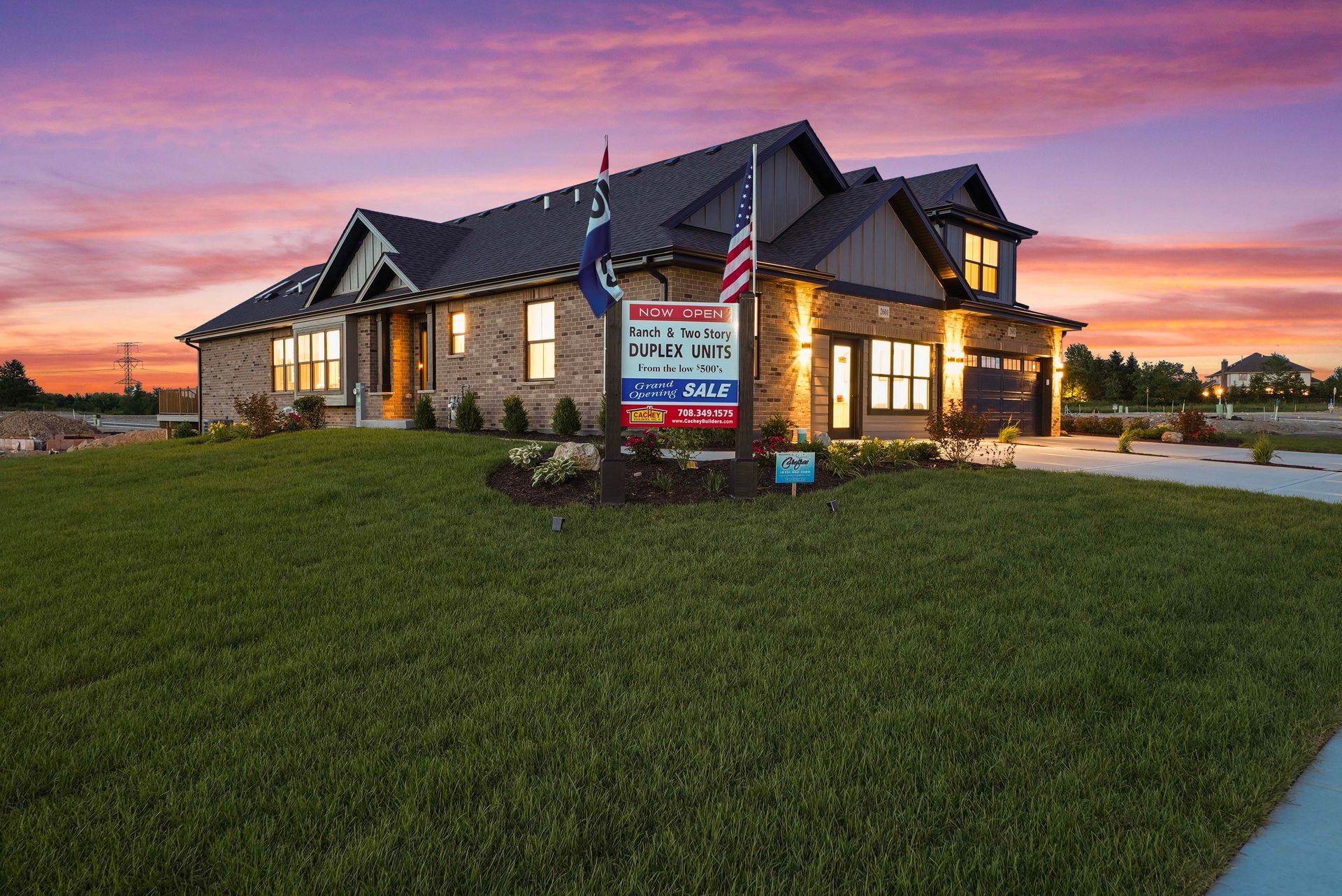 Stone office building at sunset with a large lawn and real estate sign in front