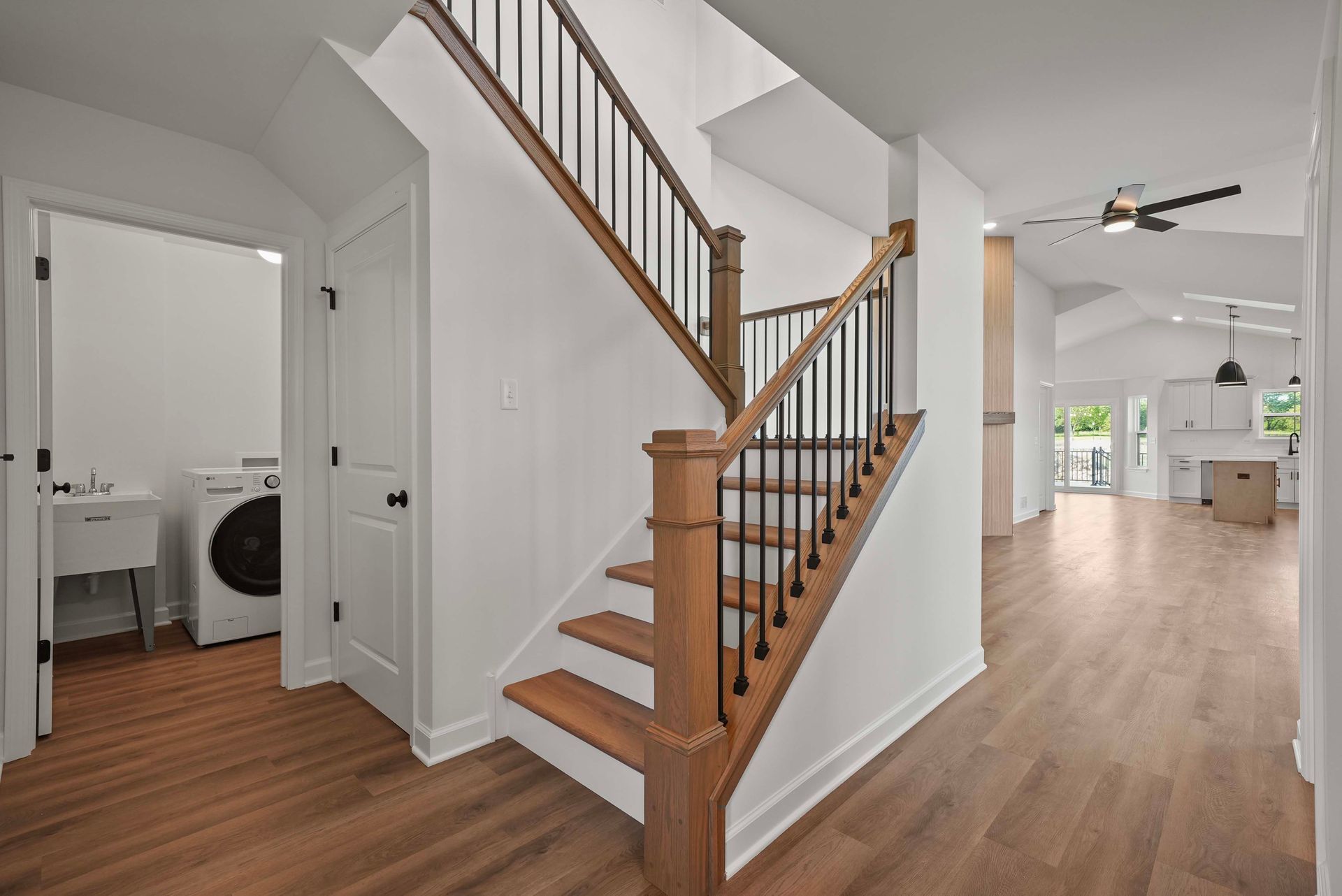 Modern home interior with wood staircase, hall bathroom, and open living area with hardwood floors