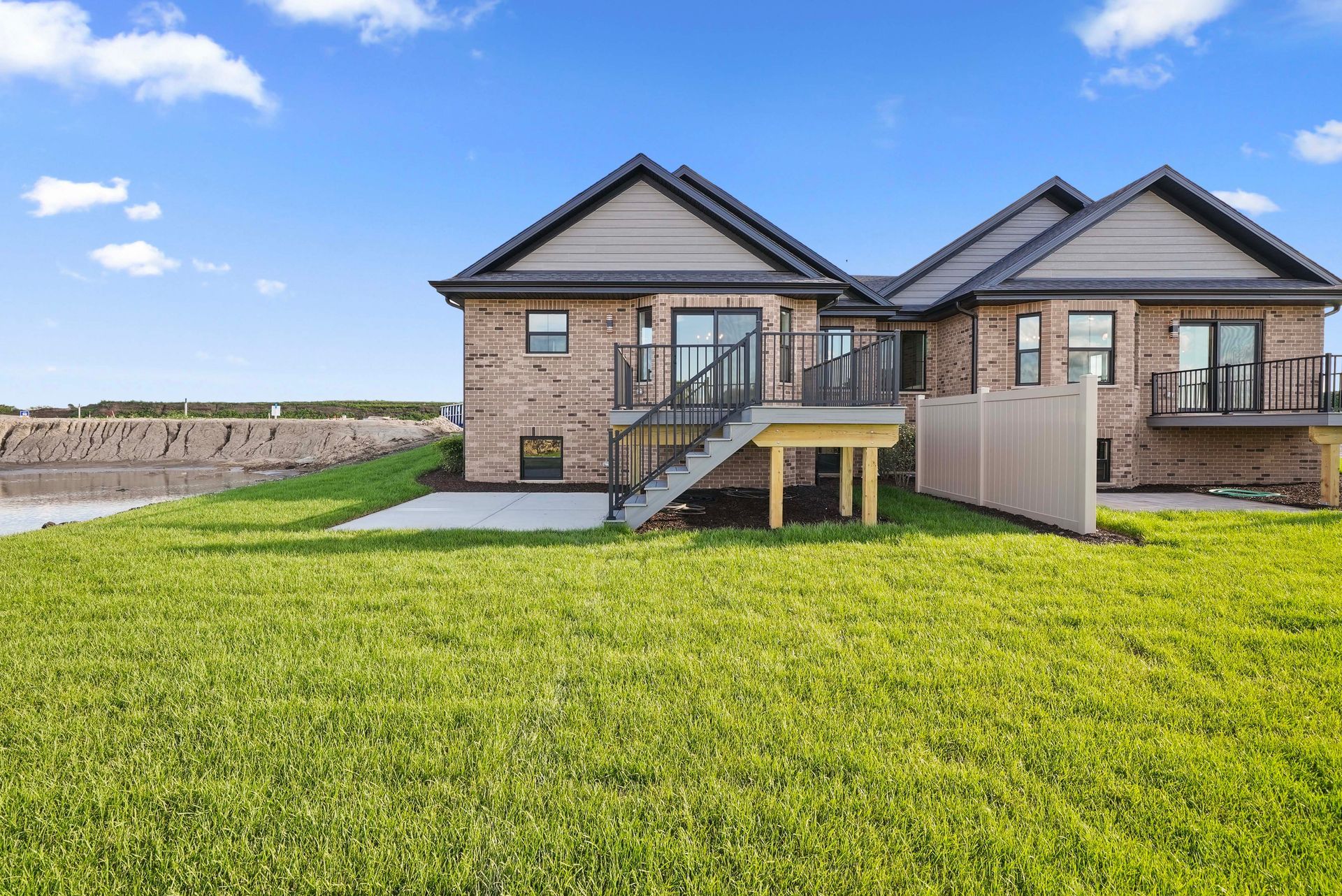 Suburban house with a large green lawn and patio under a clear sky