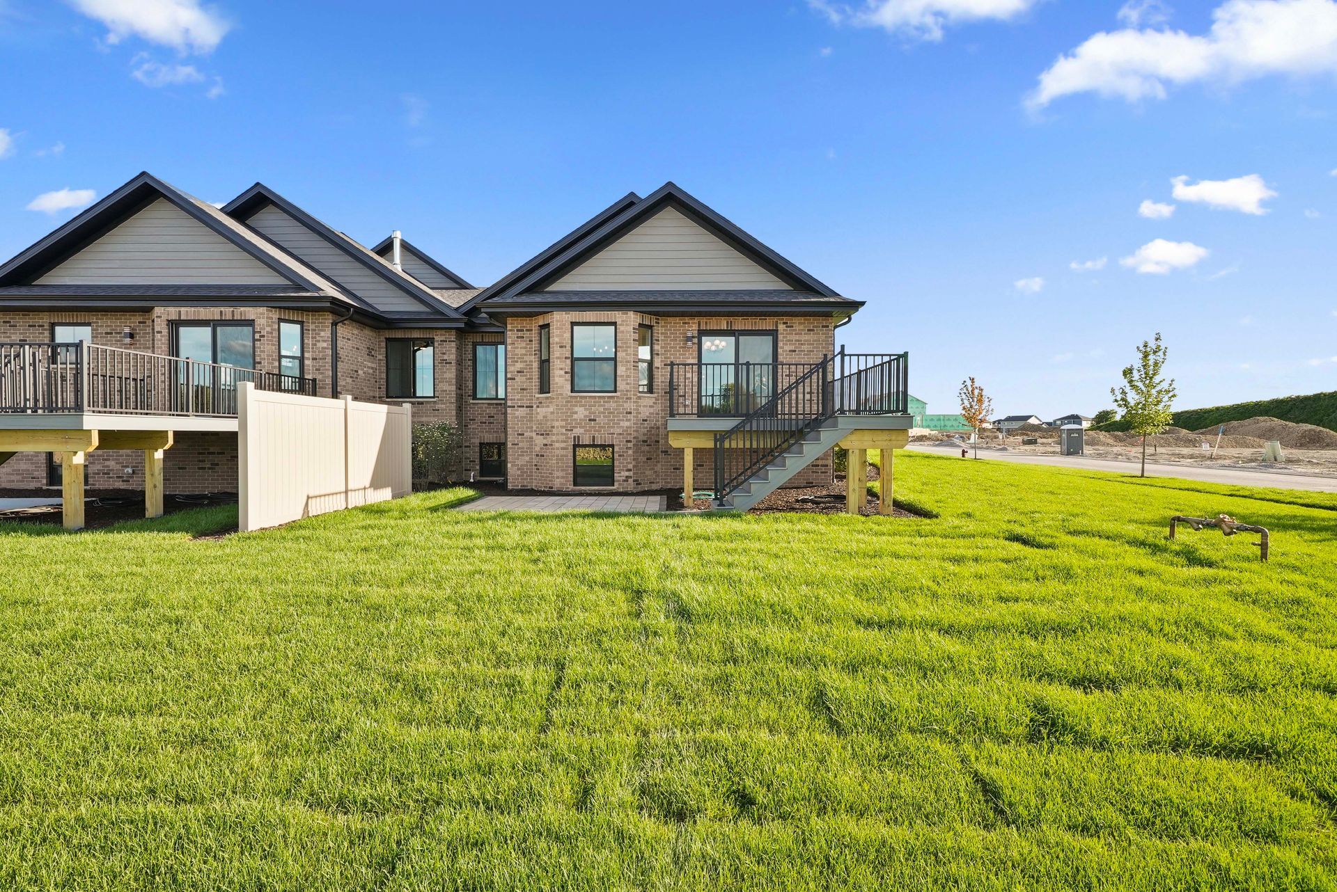 Modern brick houses with balconies overlooking a bright green field under a blue sky