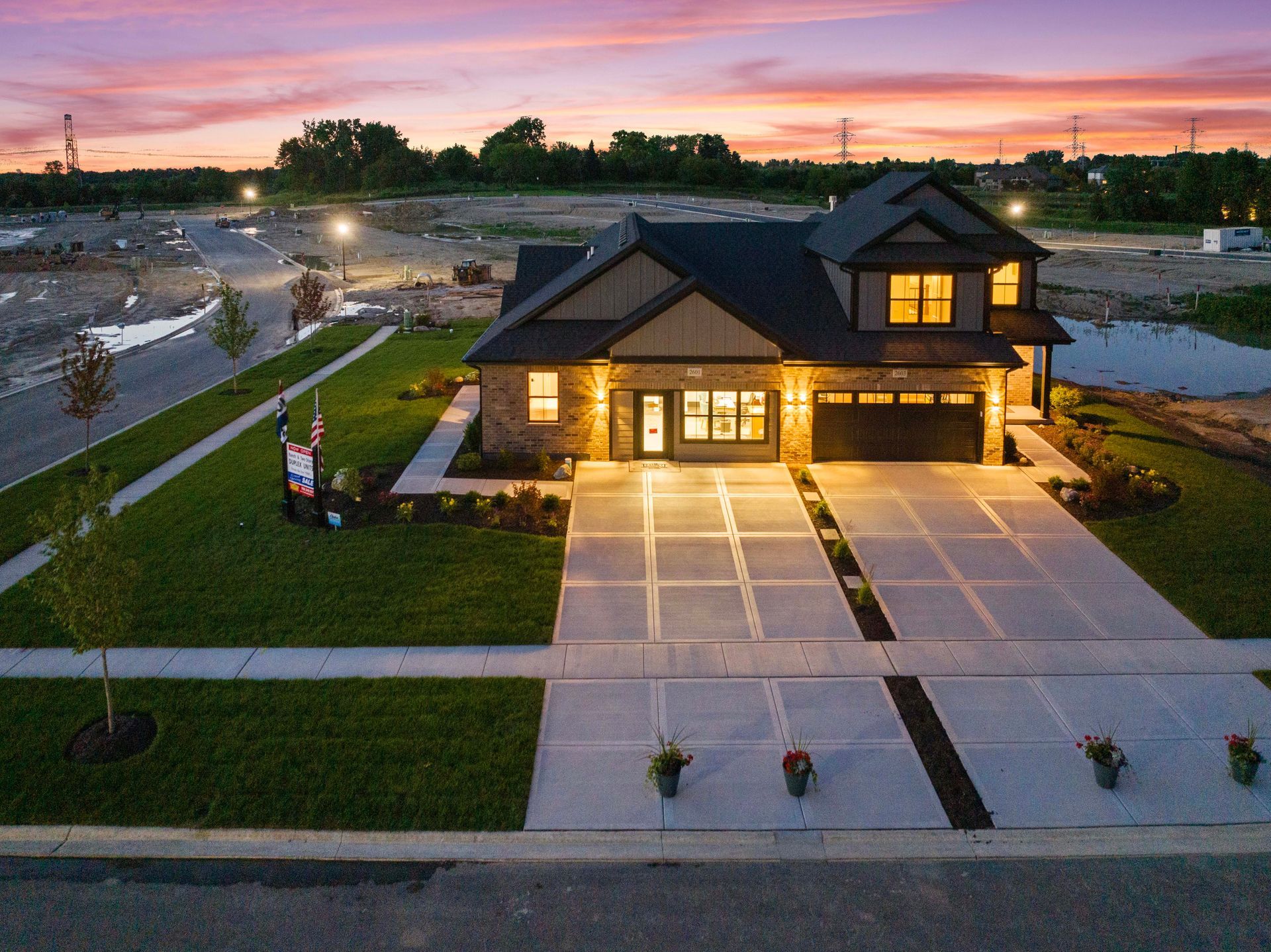 Modern house at dusk with lit driveway and sunset sky