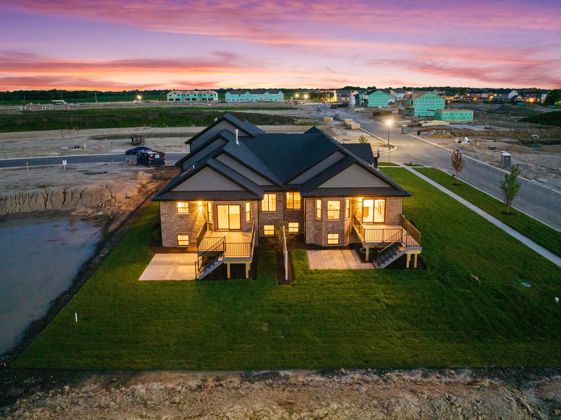 Modern house at dusk with warm lights, seen from above in a suburban neighborhood