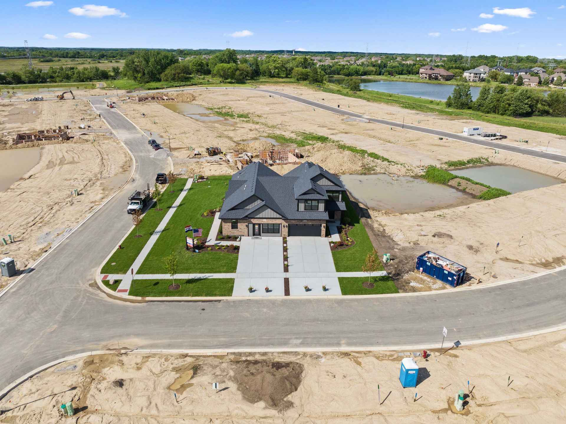 Aerial view of a new house under construction in a suburban lot with roads and cleared land.