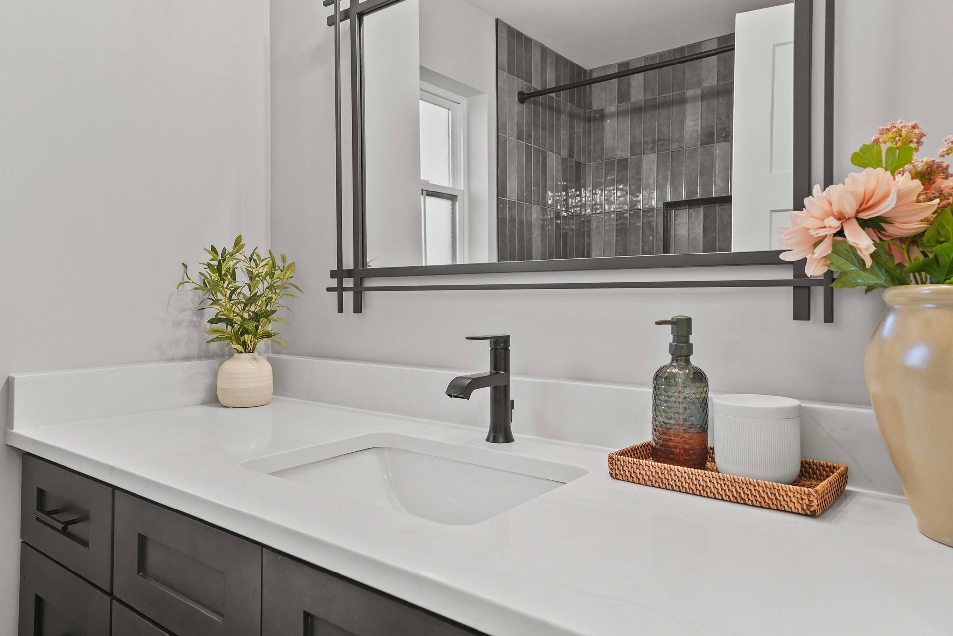 Modern bathroom vanity with black faucet, white countertop, mirror, and floral decor
