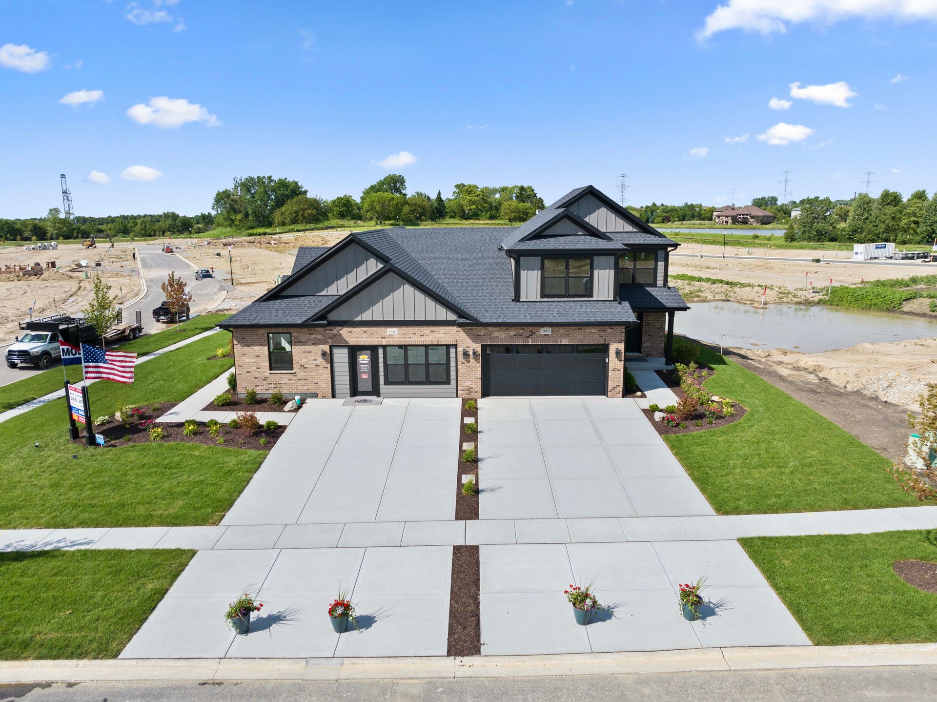 New suburban house with a wide driveway, front lawn, and stone exterior under a blue sky
