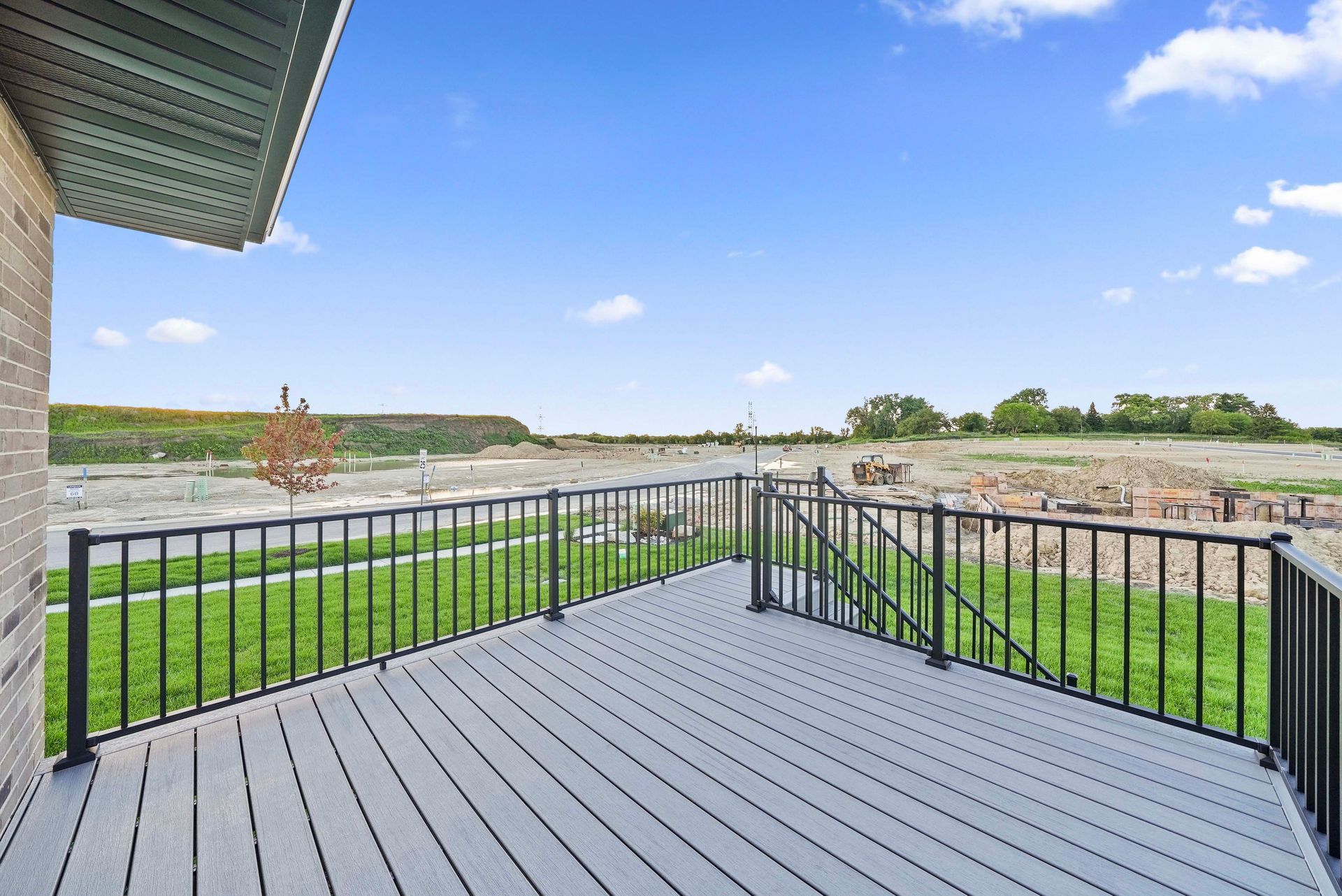 Covered deck overlooking a grassy field and river under a blue sky