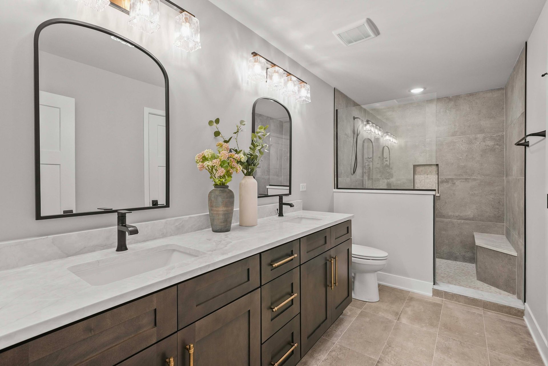 Modern bathroom with double sinks, black-framed mirrors, and a walk-in shower in neutral tones