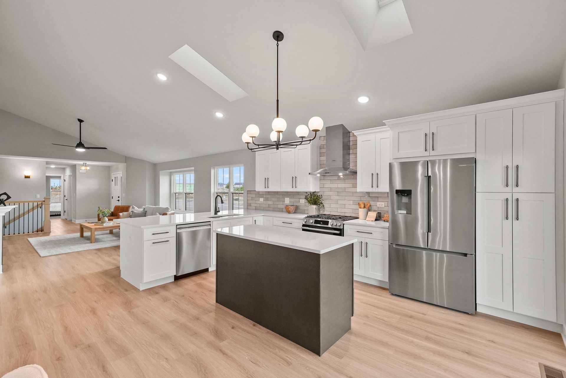 Bright modern kitchen with white cabinets, stainless appliances, island, and wood floors