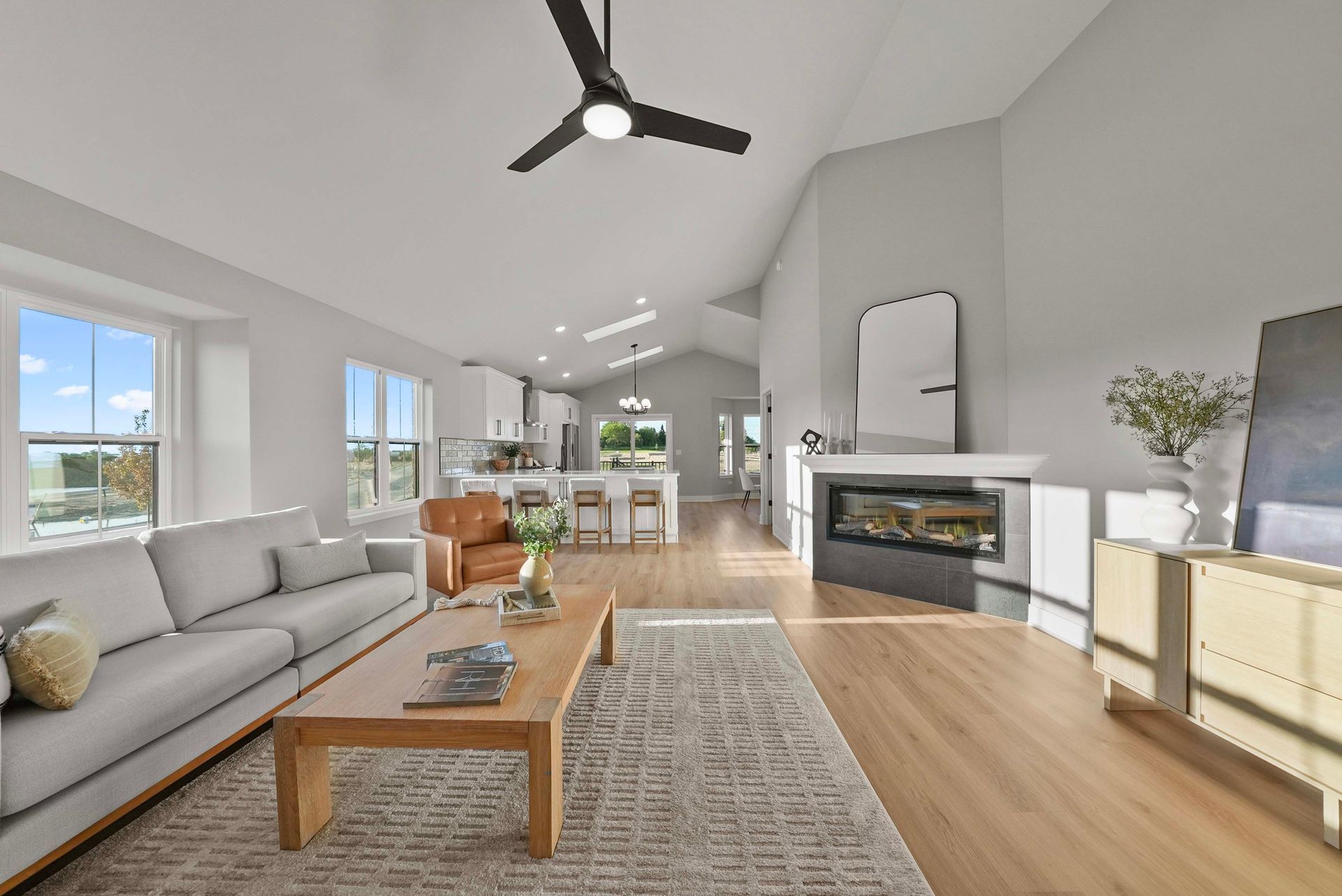 Bright modern living room with gray sofa, wood coffee table, fireplace, and open dining area