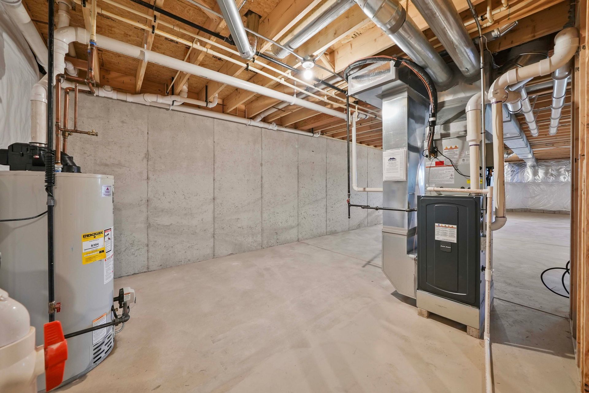 Unfinished basement with HVAC equipment, exposed ductwork, and concrete walls under a wooden ceiling.
