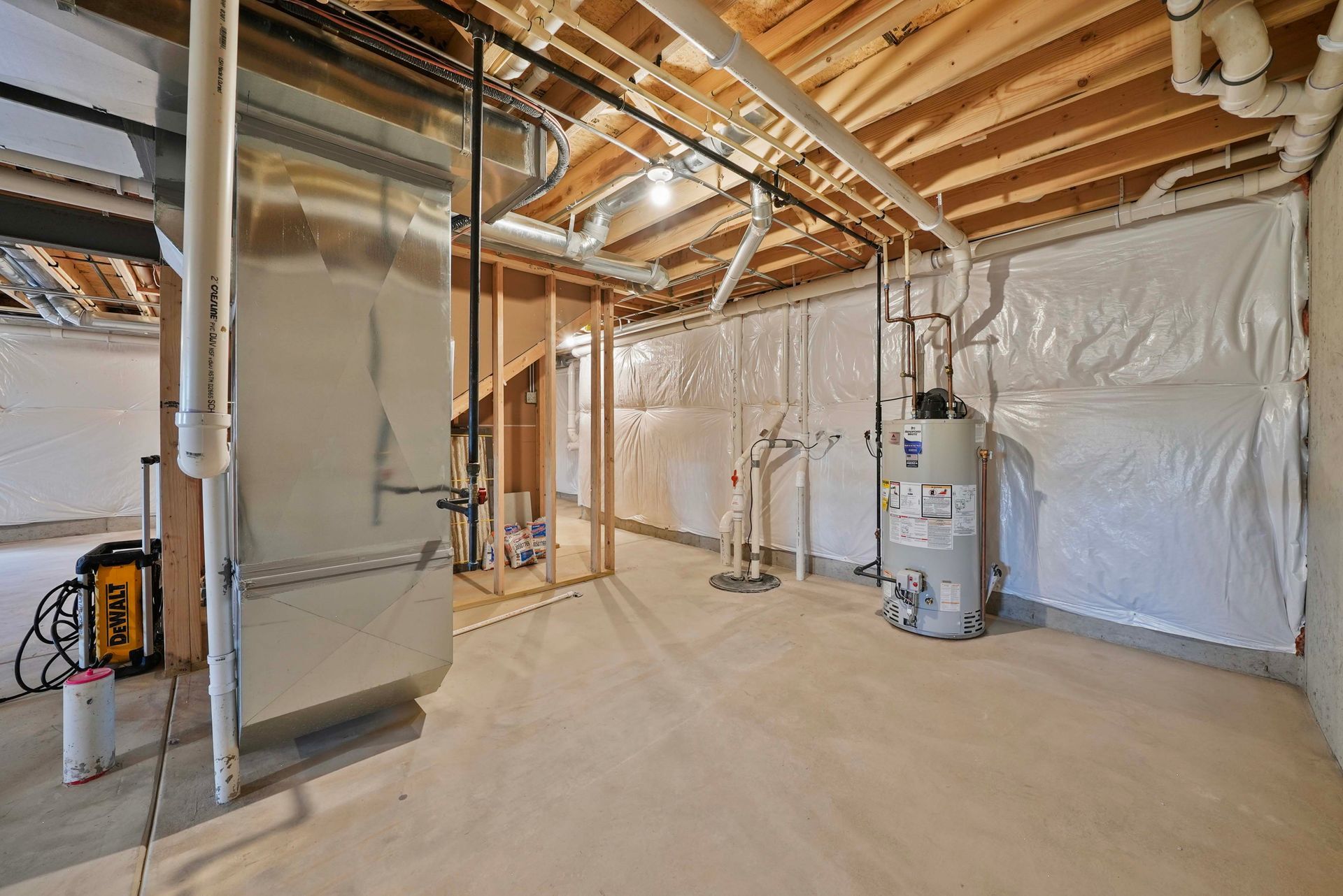 Unfinished basement with HVAC unit, exposed beams, and plastic-covered walls.
